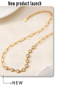 Detail of gold paperclip chain necklace with eight inlaid heart-shaped zircons on white ceramic