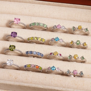 Array of minimalist rings with colorful zircons and pearls on beige velvet jewelry box