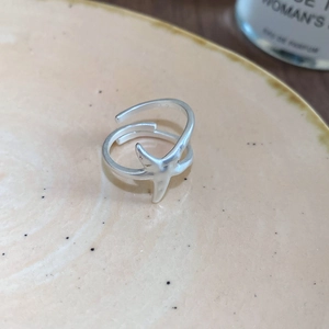 Close-up of minimalist silver starfish open ring with a matte finish on ceramic plate