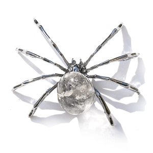 Macro detail of a decorative silver metal spider featuring a natural crystal quartz belly