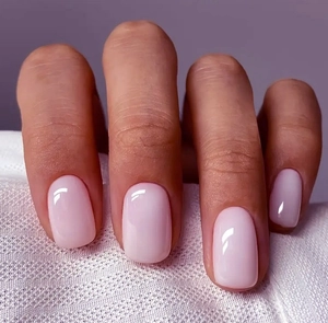 Close-up of glossy light pink press-on nails in a classic short square-oval shape