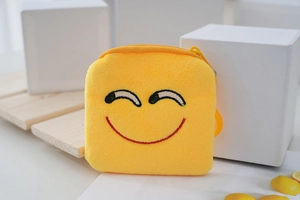 Detail of yellow plush coin purse with smiley embroidery, zipper and plastic hook clip