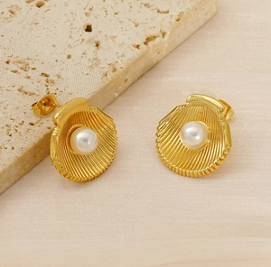 Detailed close-up of shell-shaped gold earrings with pearls on textured stone