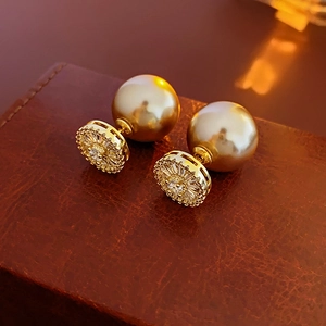 Macro view of gold-plated stud earrings featuring large pearl and sparkling zircon details