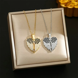 Detail view of heart-shaped angel wing pendants with inlaid gems in gold and silver