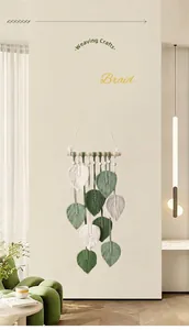 Dettaglio decorazione murale in macramè con foglie intrecciate a mano verde e crema
