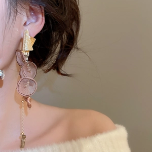 Detail of long gold tassel earrings with brown chiffon flowers worn by a female model