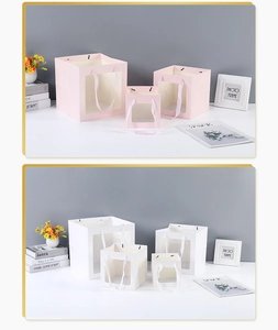 Detail of square gift bags with transparent windows and ribbon handles in pink and white