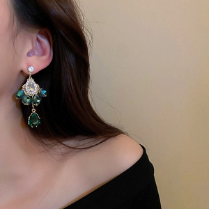 Detailed close-up of bohemian gold-tone earrings with emerald green teardrop crystals