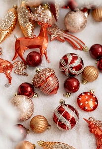 Vue à plat de décorations de Noël rouges et dorées pailletées sur neige artificielle