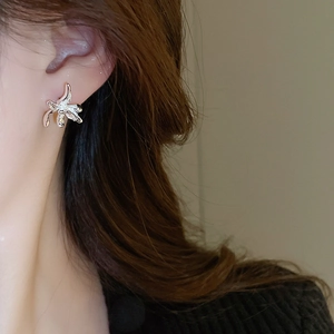 Close-up of silver metal flower earring with irregular pleated texture on a model