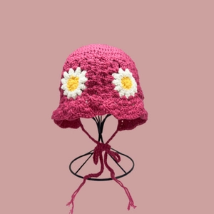 Detailansicht der handgestrickten rosaroten Fischerhut mit Häkelblumen und Bändern