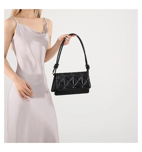 Detail of black crossbody bag with geometric quilted pattern and knotted shoulder strap