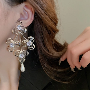 Silver flower earrings with zircons and drop pearls shown on a female model