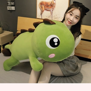 Close-up of green dinosaur plush toy with large eyes and brown dorsal fins in home setting