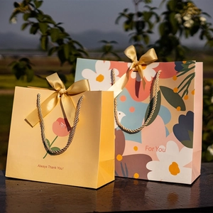 Minimalist paper gift bags with golden ribbons and floral patterns in warm sunlight