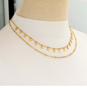 Close-up of a double-layered 18K gold plated necklace with disc charms on a model
