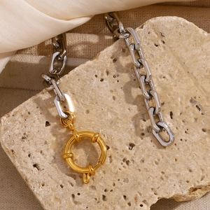 Detailed shot of two-tone stainless steel chain with gold spring clasp on stone background
