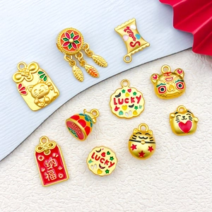 Macro detail of Lucky Cat and Fortune Bag charms in gold finish with colorful enamel