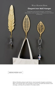 Detailed view of three gold leaf-shaped wall hooks including feather and leaf designs