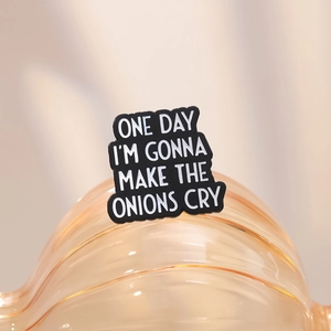 Funny black enamel pin badge with white text saying ONE DAY I'M GONNA MAKE THE ONIONS CRY