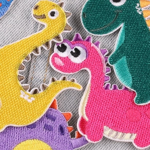 Detailed set of colorful cartoon dinosaur embroidery patches on blue denim fabric background