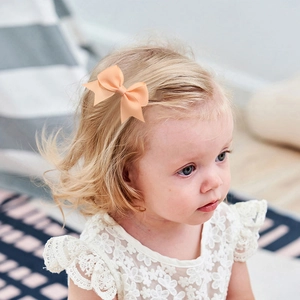 Toddler girl wearing a peach grosgrain ribbon bow hair clip in natural light setting