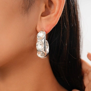 Macro view of C-shaped silver stud earrings with large round cubic zirconia crystals