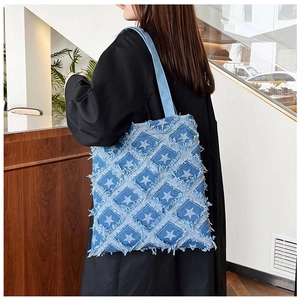 Close-up of star pattern patchwork on a blue denim tote bag worn by a model