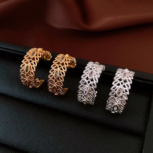 Close-up of gold and silver wheat ear earrings with zircon inlay on a luxury black display
