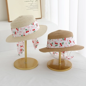 Detailed view of kids straw sun hats with cherry ribbons and elastic wind straps