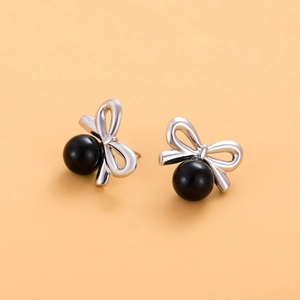 Vue détaillée des clous d'oreilles nœud argenté avec des perles noires rondes