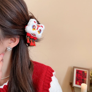 Détail d'une pince à cheveux lion en peluche avec pompons rouges pour le Nouvel An