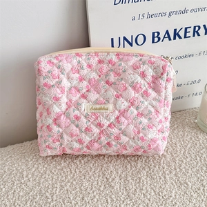Detailed close-up of pink floral quilted fabric and gold embroidered brand label