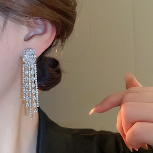 Detail of silver long tassel drop earrings featuring zircon studs on a model's ear