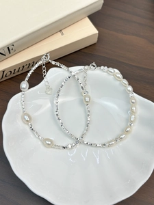 Detail showing S925 sterling silver beads and natural freshwater pearls on a white shell plate