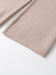 Close-up of fine knit cuffs and hem in beige oatmeal fabric showing high-quality stitching