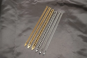 Dettaglio di bracciali a catena cubana oro e argento in tre larghezze su seta