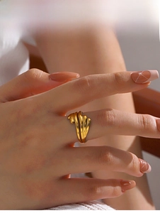 Close-up of golden wavy rippled ring featuring a textured shell pattern on model hand