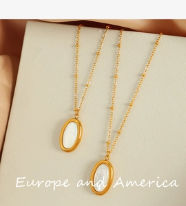 Detail of two gold necklaces with oval white shell pendants on beige silk fabric