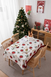 Detailed close-up of festive Christmas tablecloth with red poinsettia and green holly leaves