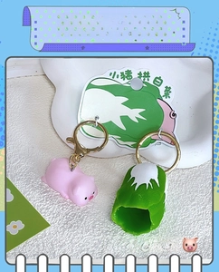 Close-up of pink pig and green cabbage charms on a creative couple keychain set