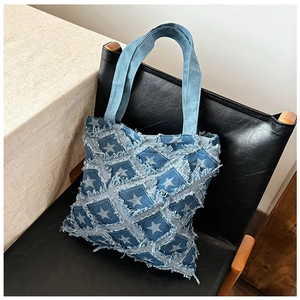 Detail of denim tote bag with star patchwork and frayed edges on a leather chair