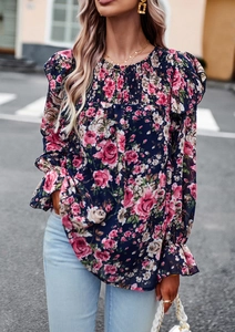 Detail of floral printed blouse featuring ruffled cuffs and a pleated neckline design
