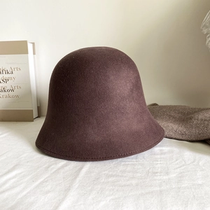 Détail de la texture d'un chapeau cloche en laine marron foncé avec un décor minimaliste