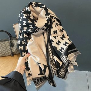 Close-up of soft cashmere texture scarf featuring classic black and beige H pattern