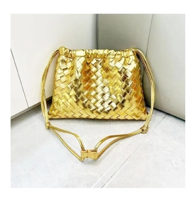 Detail of golden woven leather drawstring crossbody bag with metallic finish and knotted strap