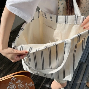 Detail of canvas tote bag with black stripes showing the spacious interior and zip pocket