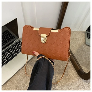 Detail of tan woven faux leather bag featuring a gold press lock and chain strap