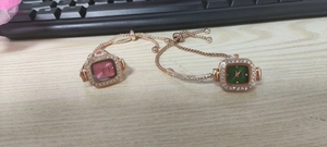 Detail of square rose gold rhinestone watches with pink and green dials on metal bracelet